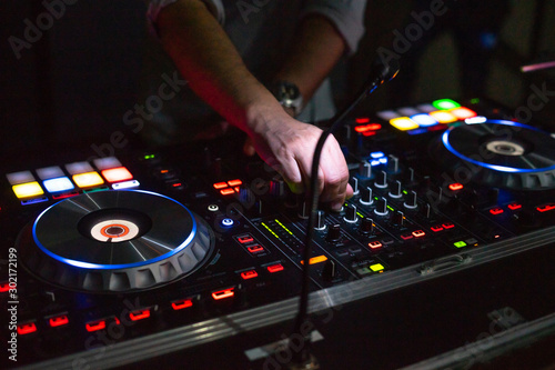 DJ desk in a nightclub party with hands. Studio DJ equipment glowing with light