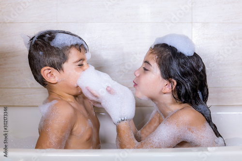 Fototapeta Two kids playing with foam in a bathtub