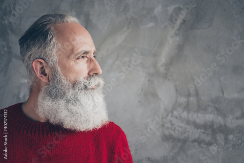 Closeup photo of nice aged guy looking side empty space minded wear red knitted pullover jumper cool hipster santa outfit isolated grey color concrete wall background