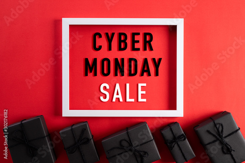 Top view of Cyber Monday Sale text on white picture frame with black gift box and on red background. Shopping online concept and Cyber Monday composition. photo