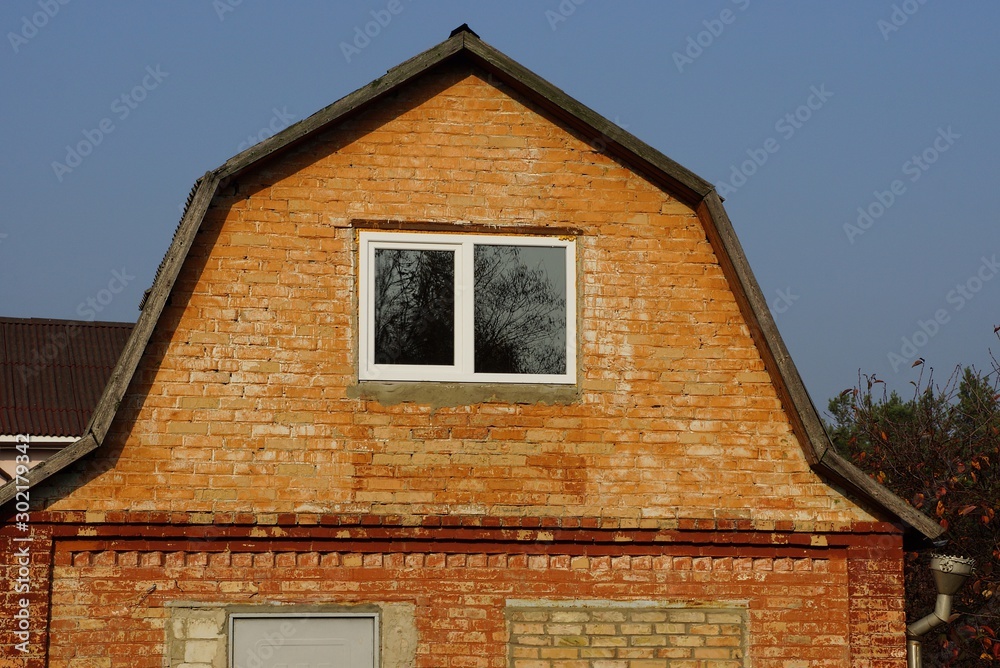 old brown loft brick house with one window on sky background old brown loft brick house with one window on sky background