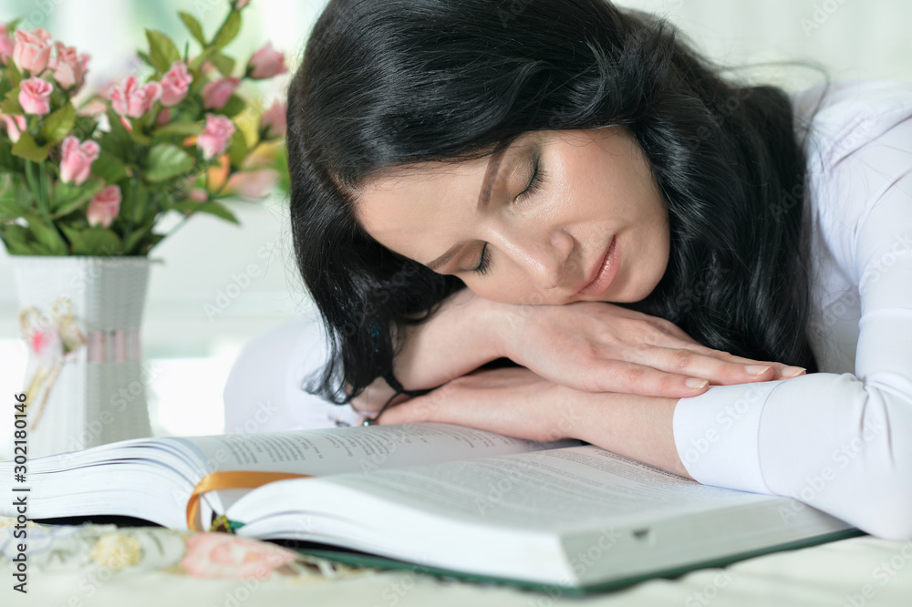 Close up portrait of young woman sleeping on opened big book Close up portrait of young woman sleeping on opened big book