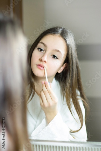Female beauty  beautiful teen girl applying make up in bathroom at home.