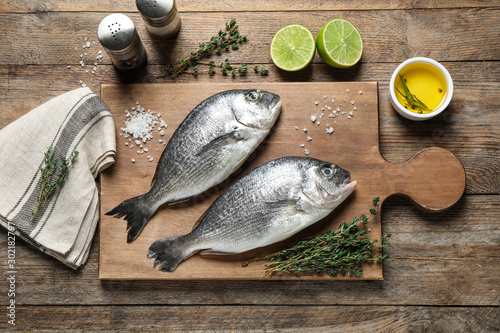 Flat lay composition with raw dorada fish on wooden table photo