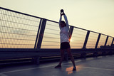 Athletic woman doing kettlebell swing exercise on the rooftop during sunset