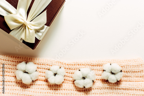 Cotton flowers on a pink jumper and gift box. Warm clothes as a present for Christmas.