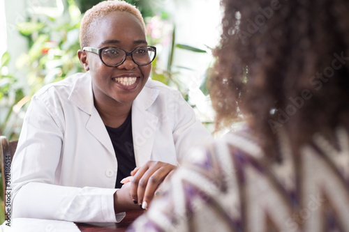 A young African American female doctor with glasses shakes hands with a patient as a sign of trust of a doctor. People of mixed race In the doctors office