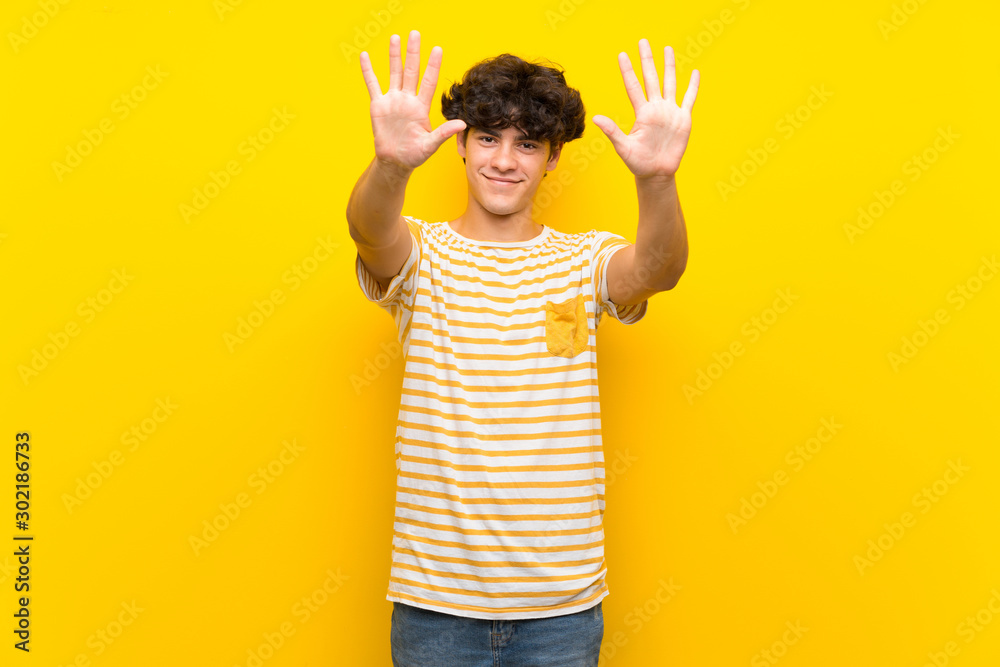 Young man over isolated yellow wall counting ten with fingers Young man over isolated yellow wall counting ten with fingers