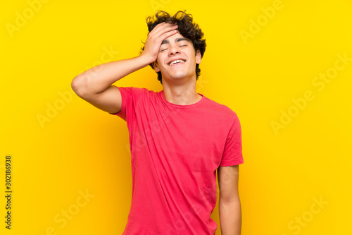 Young man over isolated yellow wall laughing