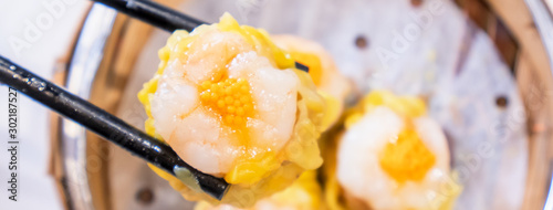 Siu Mai, one of Dim Sum yum cha, pork and shrimp steamed dumplings on restaurant house white background table for breakfast, lifestyle, close up.