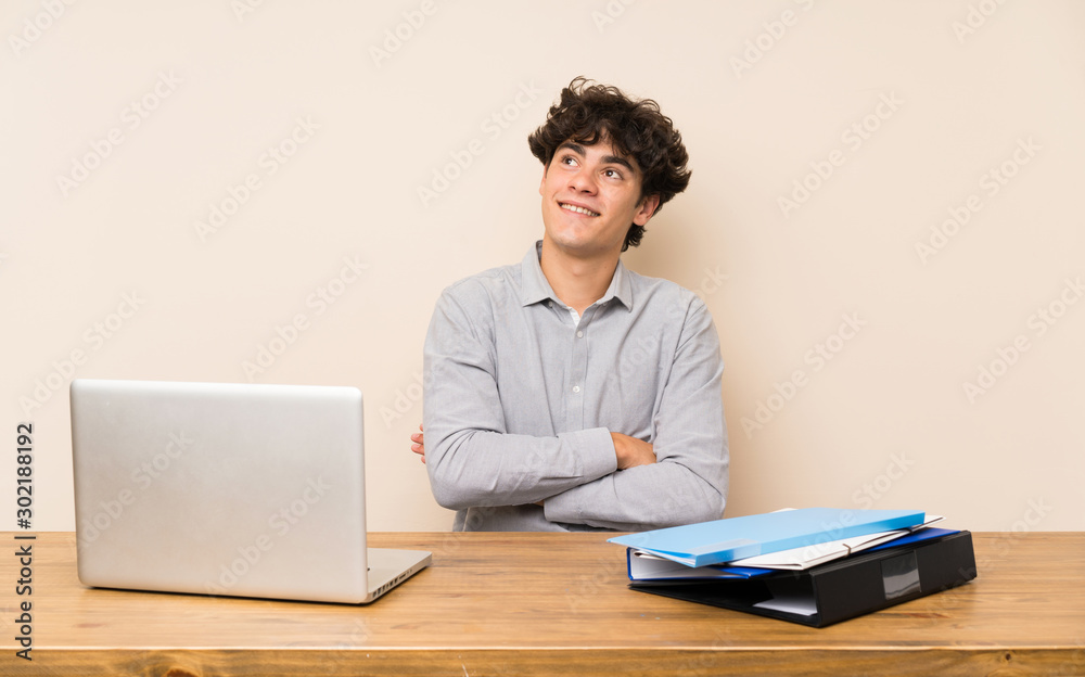 Young student man with a laptop looking up while smiling Young student man with a laptop looking up while smiling