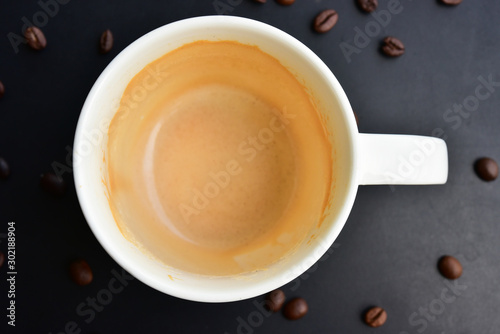 The empty cap of Coffee on the of dark wood table have many coffee beans. photo