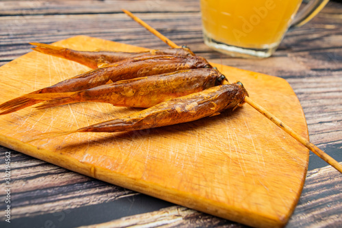 Dried mullet on a wooden Board with a mug of beer on the table. Fish and seafood cuisine. Tasty snack. photo