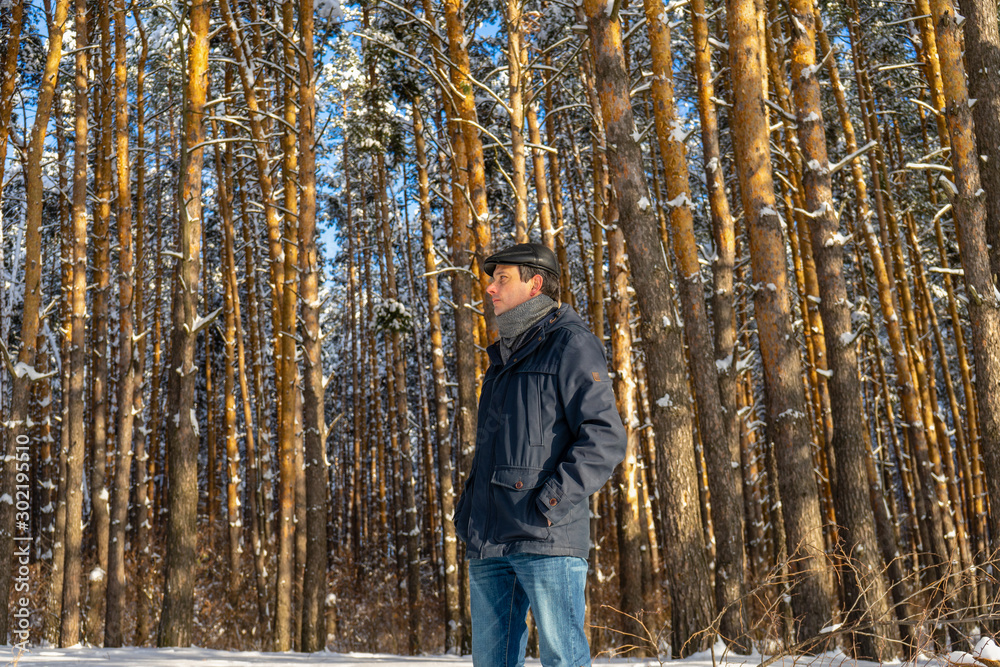 Portrait of handsome middle-aged man against beautiful winter landscape. Man walking in snowy forest in sunny frosty day. Human and nature, winter holidays, weekend at countryside concept Portrait of handsome middle-aged man against beautiful winter landscape. Man walking in snowy forest in sunny frosty day. Human and nature, winter holidays, weekend at countryside concept