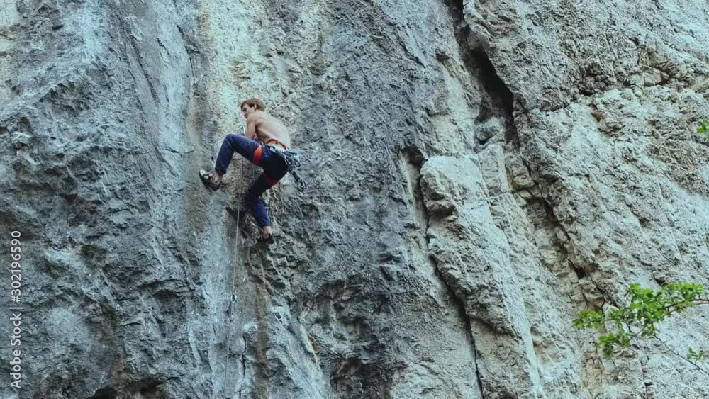 back view strong muscular man rock climber climbing on sport route outdoors on a vertical cliff, making hard wide move and gripping hold. 120 fps slow motion back view strong muscular man rock climber climbing on sport route outdoors on a vertical cliff, making hard wide move and gripping hold. 120 fps slow motion