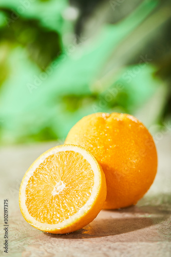 selective focus of cut and whole oranges with drops on marble surface