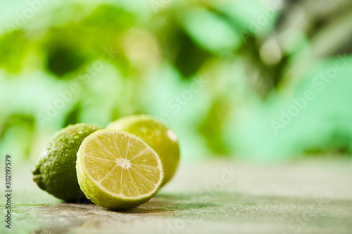 selective focus of whole and cut limes with drops on marble surface
