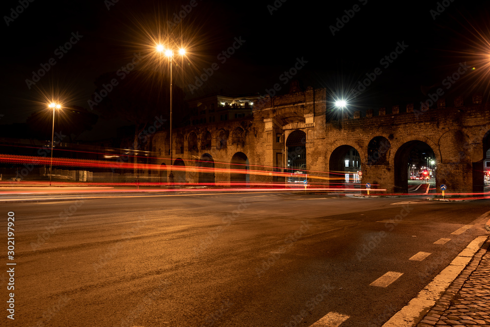 Night view of a street in San Giovanni in Rome, with the lights of cars and street lamps.