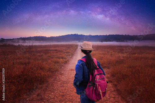 Travelers looking at Night Starry Sky Above Country Road In Countryside And Green Field. Night View Of Natural Glowing Stars. Red Ground In Red Light at  Thung Kamang nature park, Chaiyaphum, Thailand photo