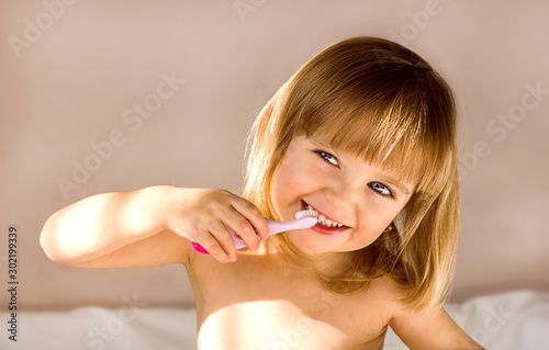 Happy baby girl brushing her teeth. Oral hygiene concept. Place to insert text