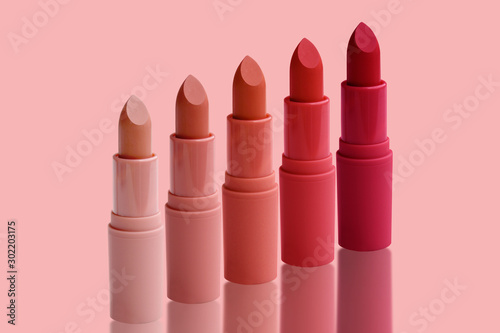 set of matte lipstick on a delicate pink background, red, raspberry, pink, coral, peach color, close-up, the concept of decorative cosmetics photo