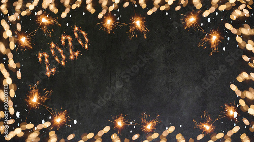 Silvester background banner - Frame made of bokeh lights, sparklers and snowflakes on dark black grey concrete texture - top view with space for text