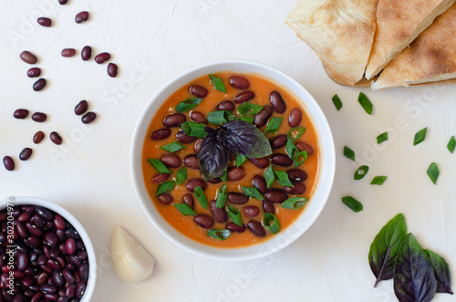 Bean puree soup with tomato, garlic, basil, onion and tandoor bread. Vegetarian food concept. Horizontal orientation. Flat lay.