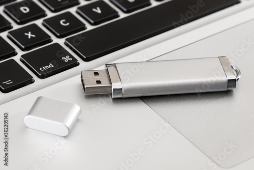 A silver USB flash drive on a laptop computer. 