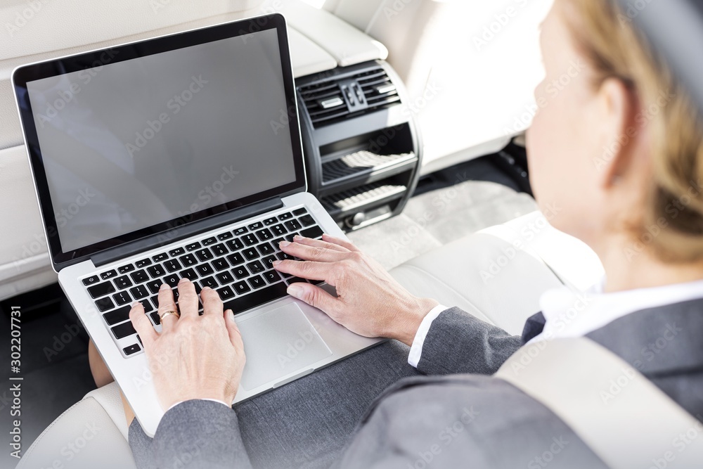 Mature businesswoman typing on laptop in car