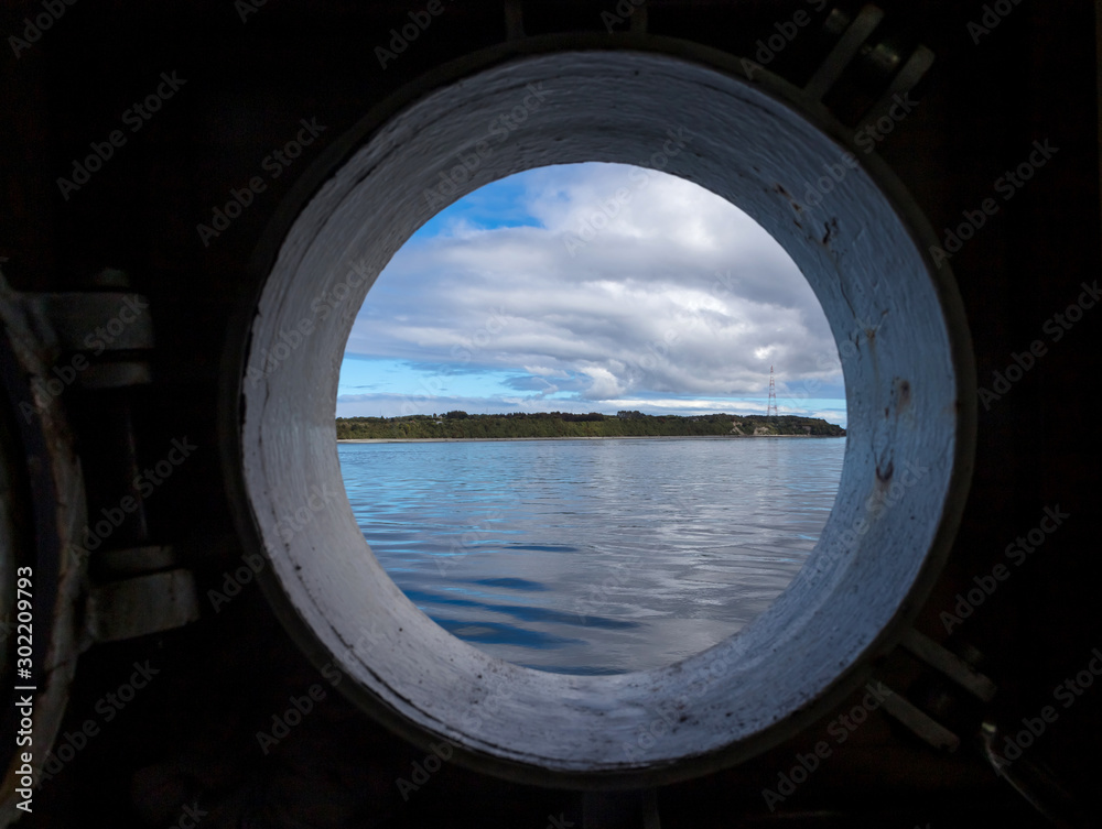 View of land and clouds through ship porthole