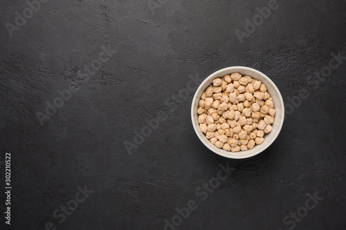 Bowl of chickpea on a textured wooden black background. Vegetable protein healthy food