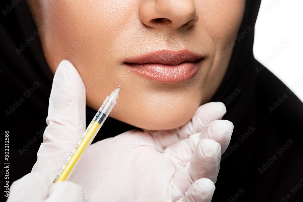 cropped view of young Muslim woman in hijab having beauty injection isolated on white, lip augmentation concept cropped view of young Muslim woman in hijab having beauty injection isolated on white, lip augmentation concept