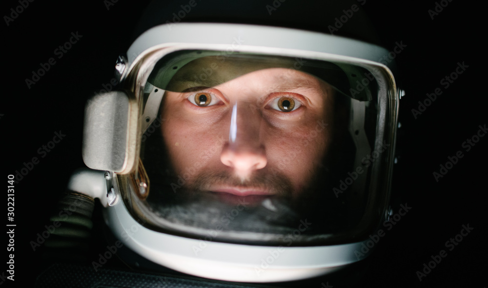 Astrounaut man in a helmet looking ahead exploring the earth in a dark Astrounaut man in a helmet looking ahead exploring the earth in a dark