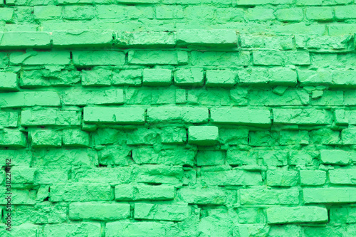 Green brick background texture of old brick masonry with elements of destruction, painted in green color