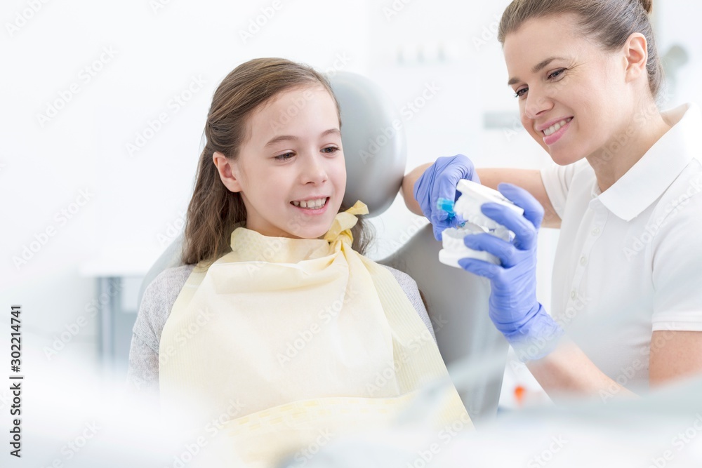 Dentist showing dentures to child patient in clinic Dentist showing dentures to child patient in clinic
