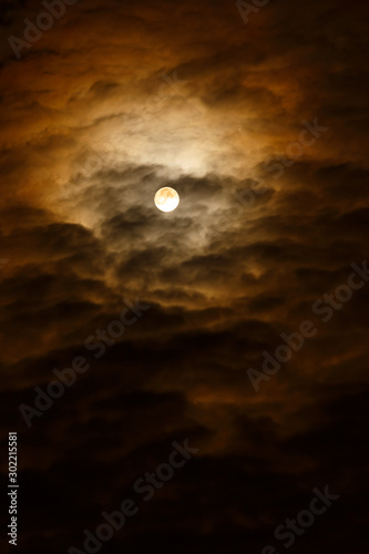 A dark cloudy sky with a full moon.Night sky with clouds.Vertical frame