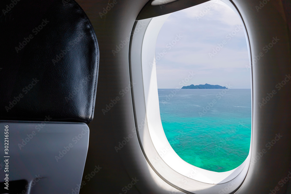 Window View From Passenger Seat On Commercial Airplane. The beautiful blue sea in Thailand.