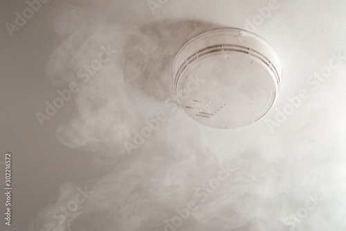 Photos Fire alarm system and home security conceptual idea with smoke rising to the cei
