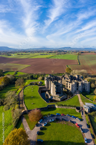 Aerial view of a large medieval castle showing the turrets, walls and moat (Raglan Castle, South Wales)