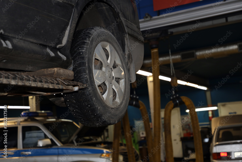 car on a lift in the garage for maintenance, wheel closeup car on a lift in the garage for maintenance, wheel closeup