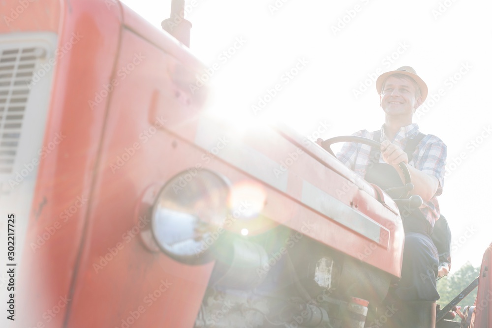 Mature farmer driving tractor in field - obrazy, fototapety, plakaty 
