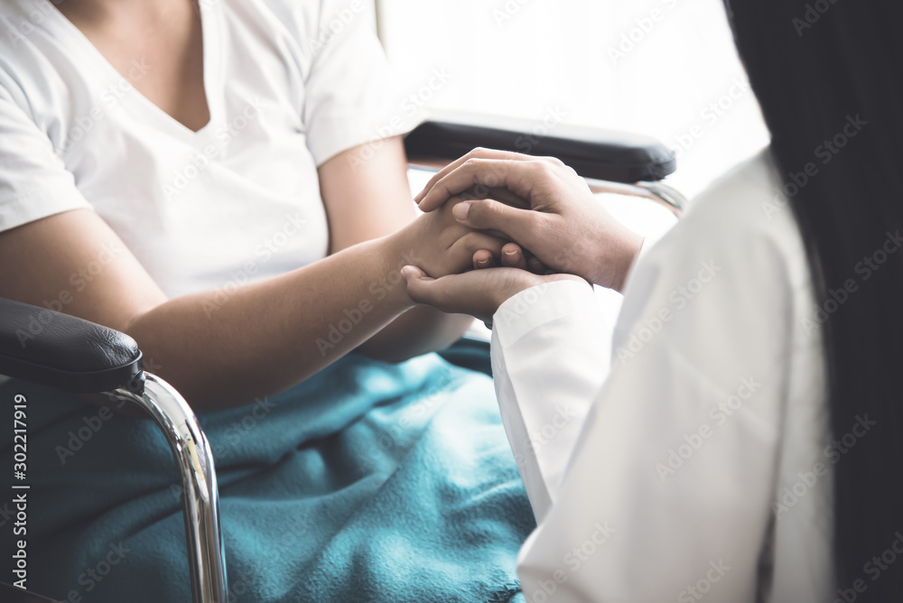 Obraz premium The doctor hold hands patient Which sat on wheelchair to encourage To fight the disease And cheer to receive treatment, to health care concept.