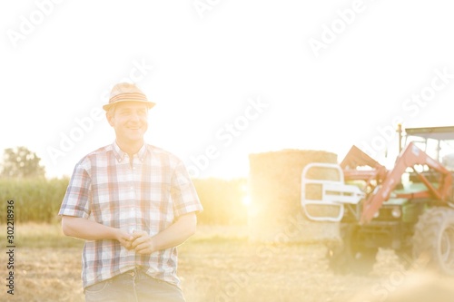 Mature farmer standing in field with lens flare in background © moodboard