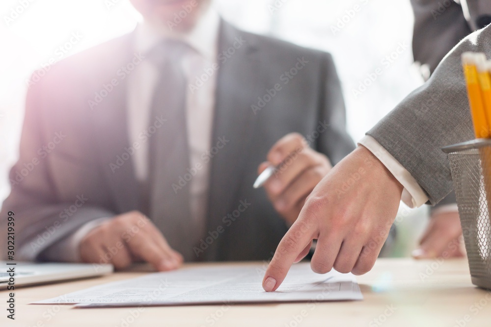 Hand of businesswoman pointing at document to senior businessman in office