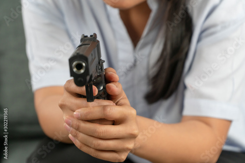Depressed middle-aged women holding a gun in living room due to stress in life and unable to find a solution and no advisor. Concepts of social issues, stress, and relationships in the family.