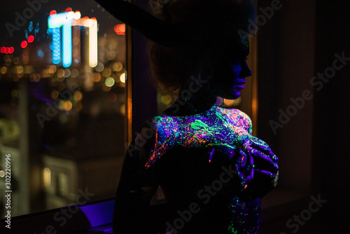 Foto Woman in multi-colored drops of ultra-violet paint with Neon String Lights