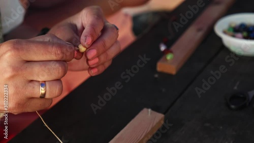 Close-up of female hands stringing beads on a thread, making a jewelry bracelet