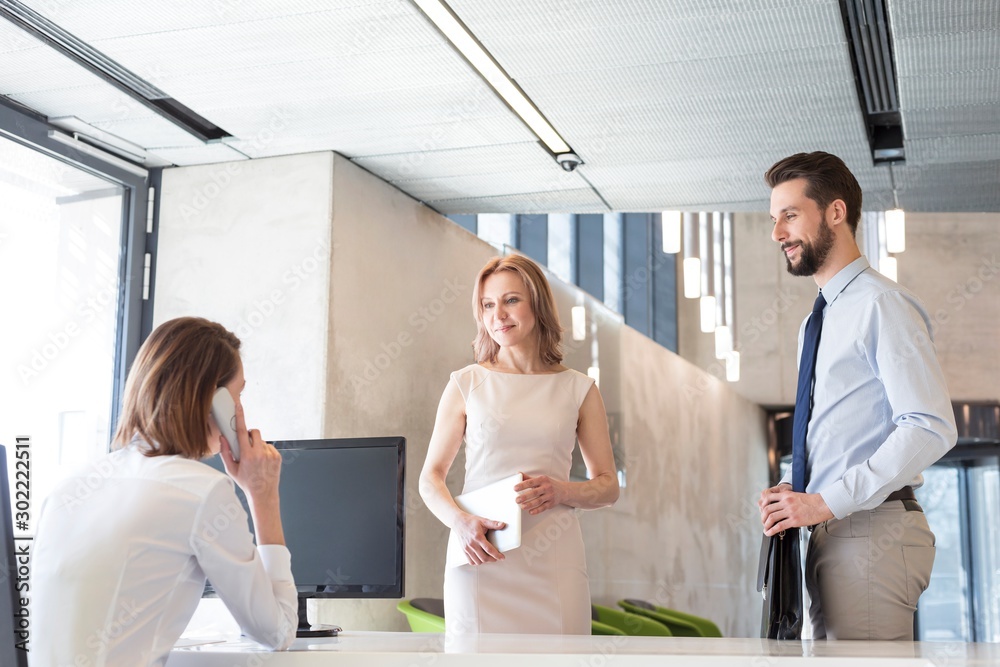 Fototapeta premium Receptionist calling manager while business people waiting in office lobby