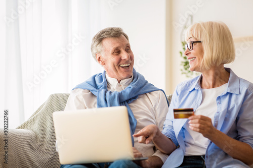 Modern mature couple shopping online on laptop