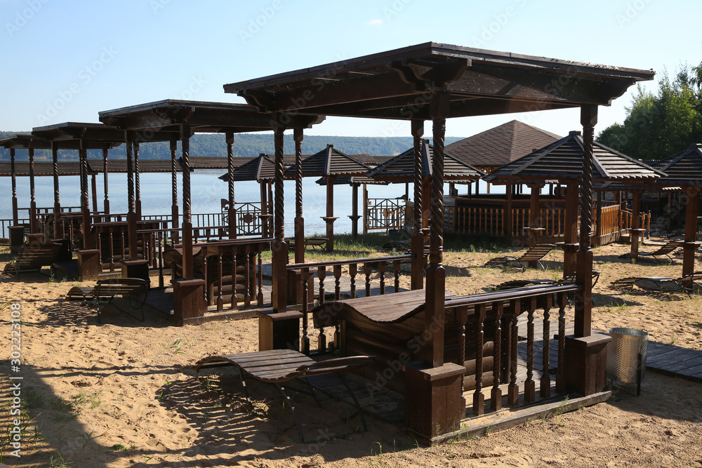 Fototapeta premium Wooden sunbeds and umbrellas on a deserted beach in low season.